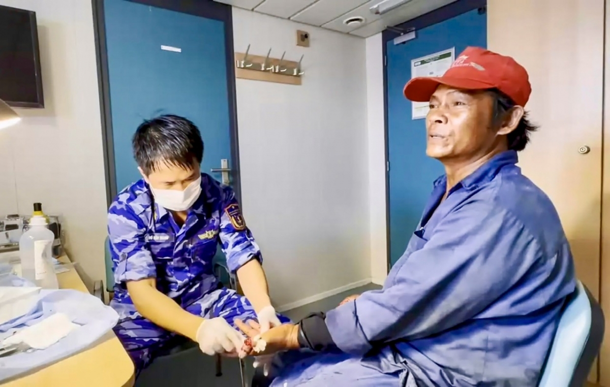 Ngư dân Nguyễn Tấn Tiến đang được nhân viên y tế cảnh sát biển sơ cứu ban đầu