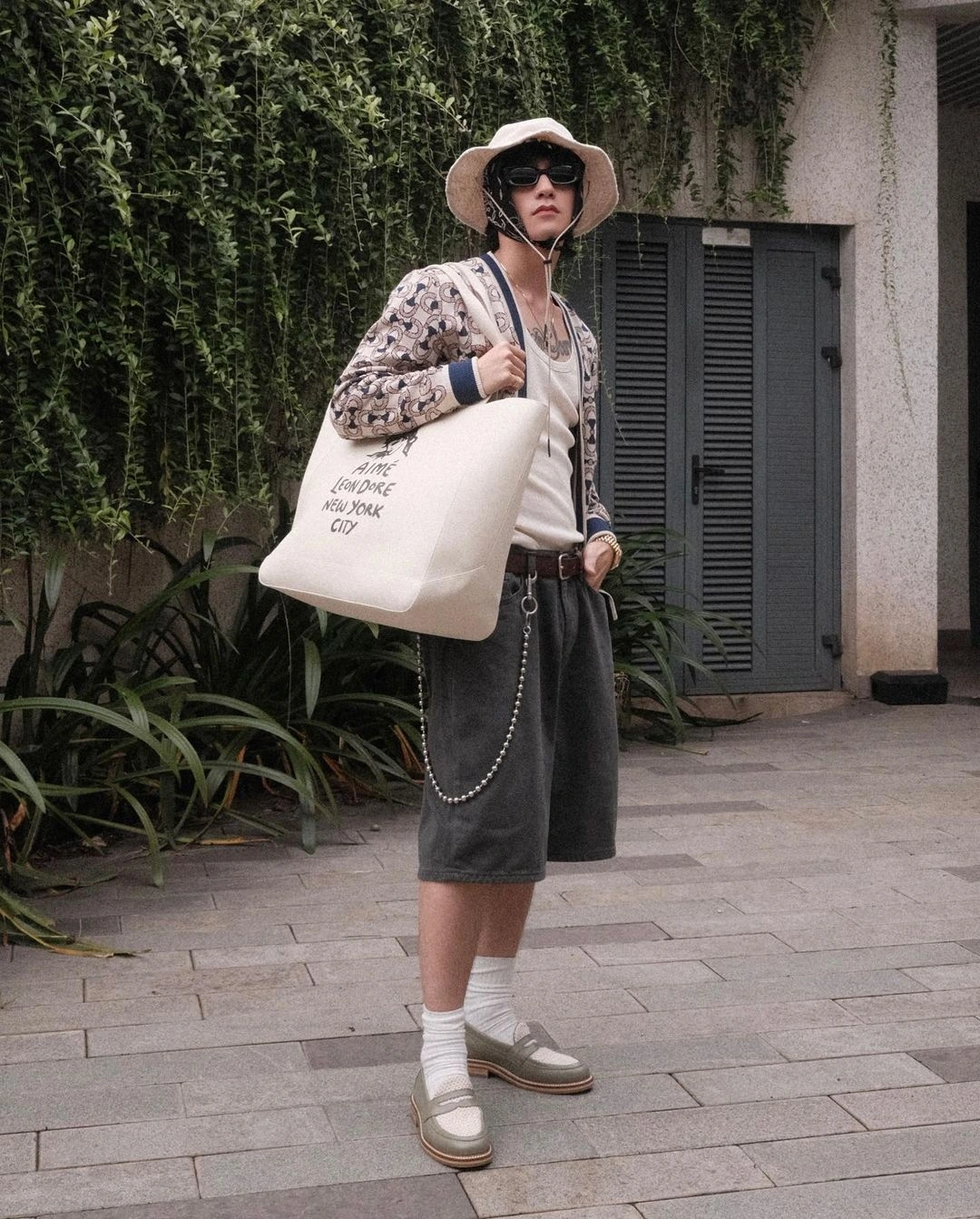 Vẫn là quần shorts ống rộng, lần này Sơn Tùng M-TP kết hợp cùng cardigan và giày loafer. Điểm nhấn của bộ trang phục là kiểu thắt khăn như cụ bà và chiếc mũ tai bèo. Gucci, Louis Vuitton... là những thương hiệu xa xỉ xuất hiện thường xuyên trong tủ đồ của anh.