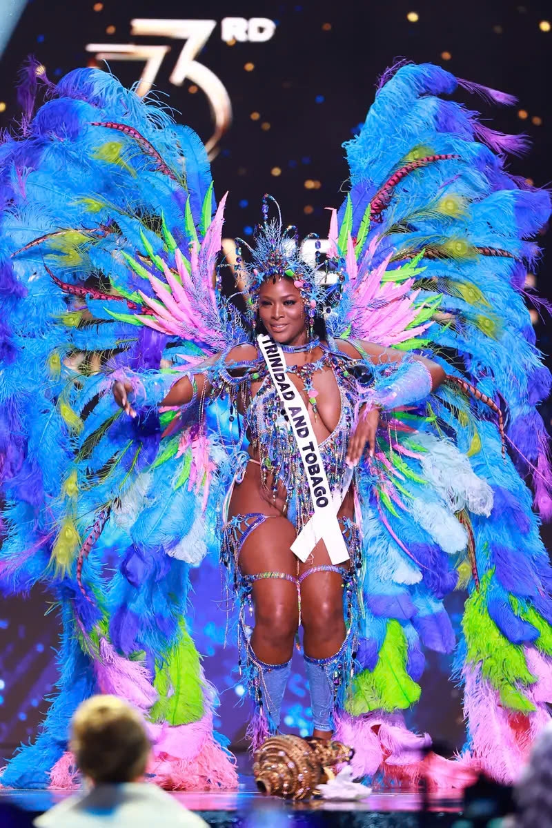 Hoa hậu Trinidad and Tobago, Jenelle Thongs, đã tái hiện vẻ đẹp rực rỡ của những rạn san hô tại quê hương cô trên sân khấu Miss Universe. Thongs đã thắp sáng sân khấu bằng bộ trang phục liền thân và đôi cánh lông vũ khổng lồ.
Cả hai món đồ đều được thiết kế với những sắc màu neon rực rỡ như hồng, xanh lá và xanh dương, mô phỏng gam màu kỳ thú của thế giới đại dương. Một điểm nhấn khác trong trang phục của cô là chiếc băng đô hình san hô, được đính đầy vỏ sò, đá quý và những miếng nhỏ hình sao biển, đồng điệu với họa tiết trang trí trên bộ đồ liền thân.