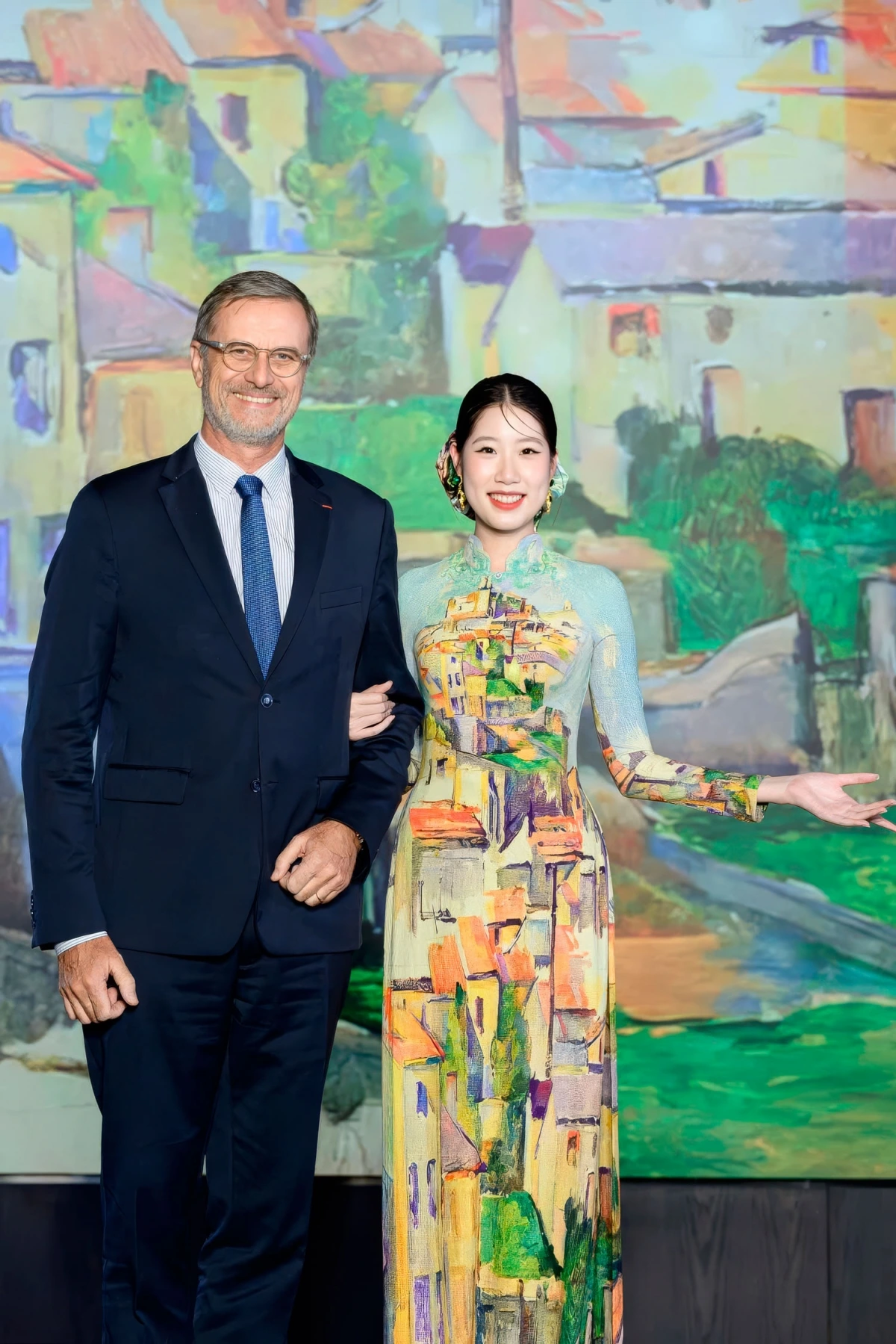 French Ambassador to Vietnam Olivier Brochet (L) attends the event. The model wears an Ao Dai depicting Gardanne town by French painter Paul Cézanne.