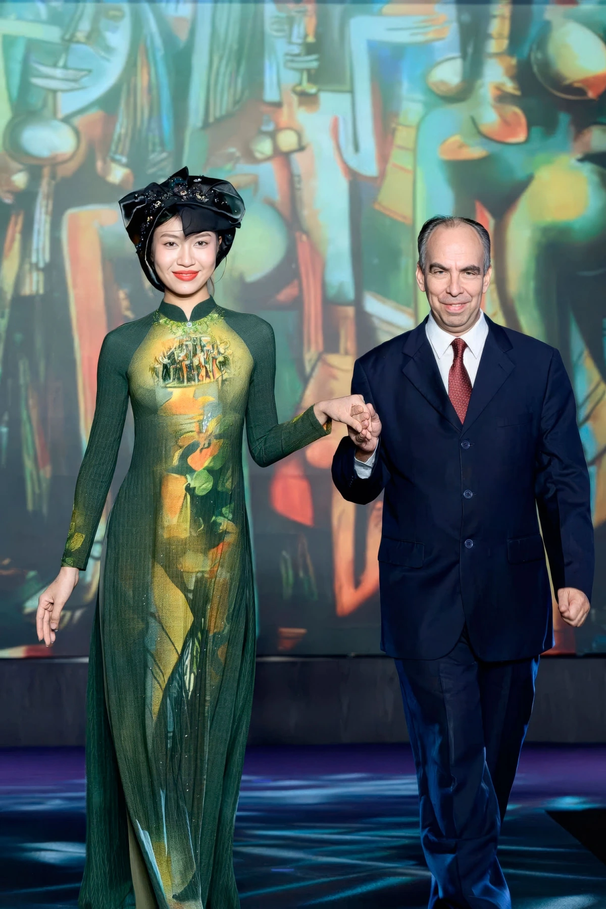 Cuban Ambassador to Vietnam Polanco Fuentes (R) joins in the show. The model dresses in an Ao Dai inspired from "The Jungle" painting by Wifredo Lam.
