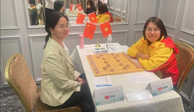 Local chess player Nguyen Hoang Yen (right) loses out to Chinese master Liu Huan (Photo: nld.com.vn)