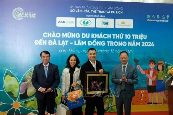 Leaders of Lam Dong province People's Committee present gifts to Nguyen Dang Dung (second from the right), a tourist from Hanoi - its 10 millionth tourist of the year