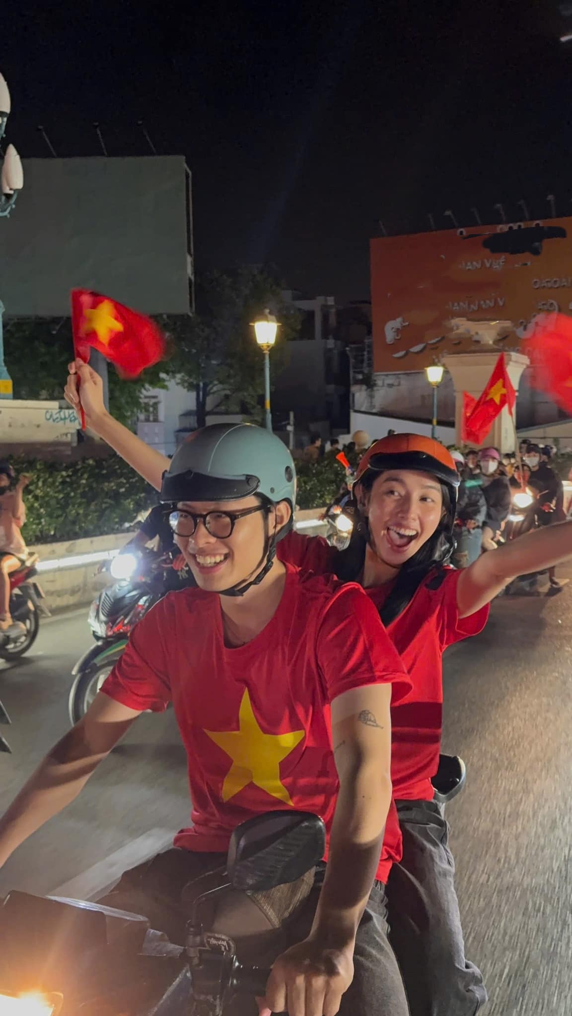 Hoa hậu Thùy Tiên và rapper HURRYKNG mặc áo cờ đỏ sao vàng, tay cầm cờ Việt Nam, xuống đường "đi bão".