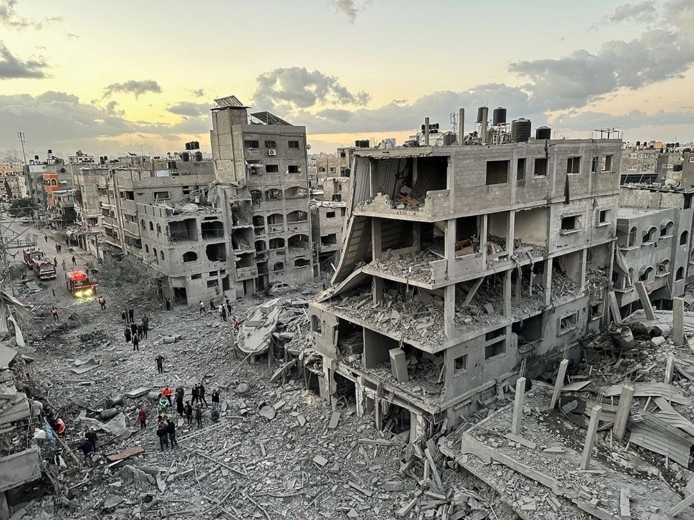 Người dân Palestine đi bộ giữa những tòa nhà đổ nát sau cuộc không kích của Israel. Ảnh: Reuters