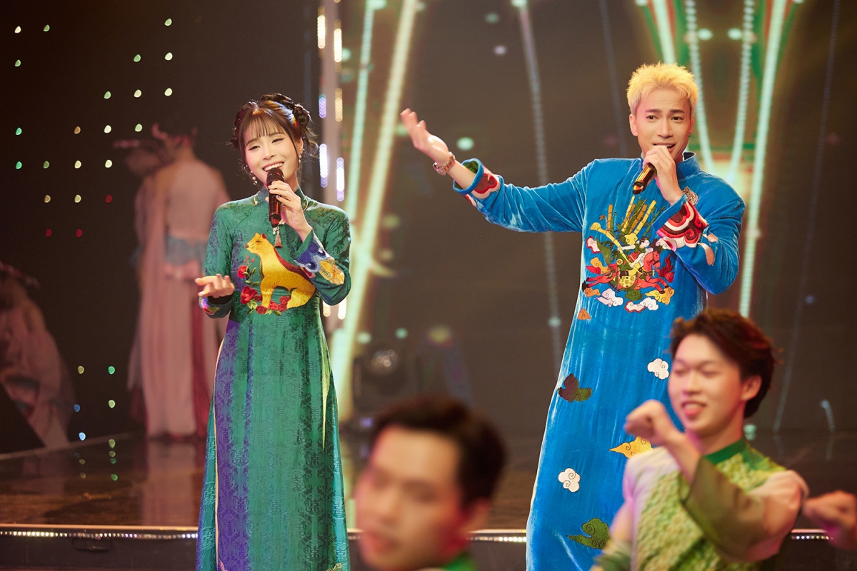 Ca nương Kiều Anh trong bộ áo dài lụa, hoạ tiết linh vật tuổi Tuất. Cô nổi bật trong sắc xanh lam. ST Sơn Thạch trong bộ áo dài xanh da trời, hoạ tiết vân mây và thêu tay con ngựa “Thánh Gióng” cưỡi mây, những hoạ tiết phụ hoạ cây tre trăm đốt gợi liên tưởng gần gũi về truyền thuyết của dân tộc Việt.