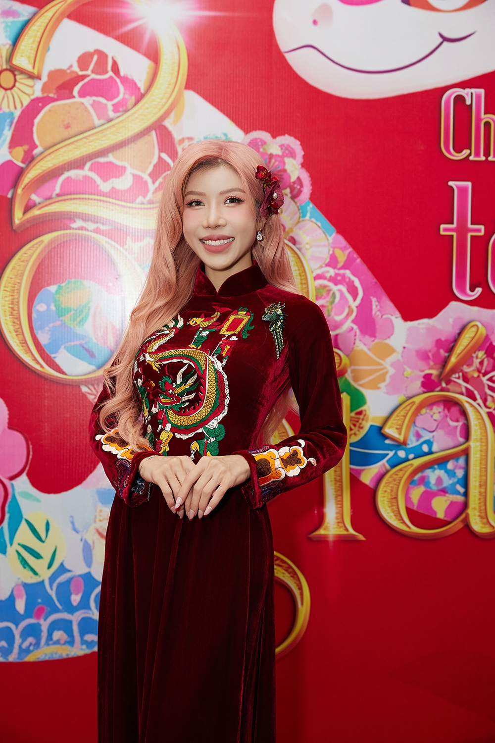 Trang Pháp mang con giáp Thìn trong trang phục áo dài nhung tone đỏ, thêu hoạ tiết bức múa rồng - tranh dân gian đông hồ. Cô điểm xuyết thêm bông hoa tỏ cài mái tạo nét dịu dàng và nữ tính hơn trông thấy.
