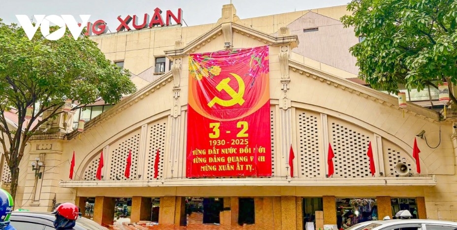 Dong Xuan market is decorated with national flags, flowers, and posters in celebration of Tet and the Communist Party of Vietnam's 95th anniversary.
