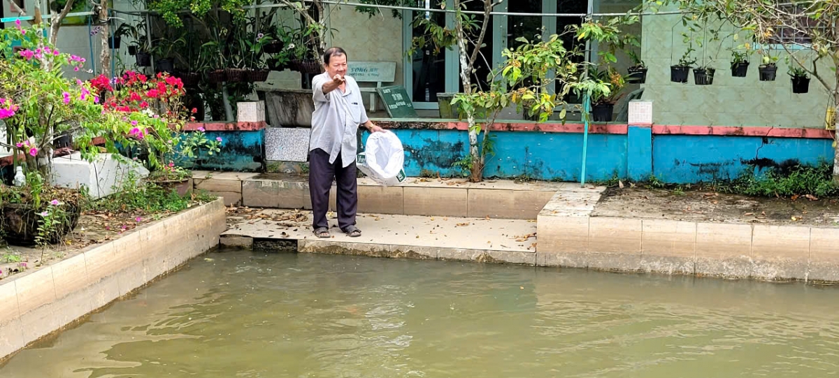 Ông Nguyễn Văn Bảy bên ao cá 