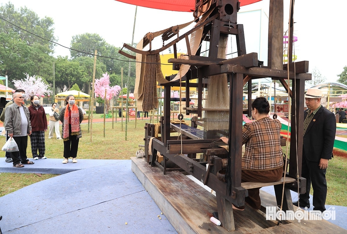 A performance of silk weaving draws attention from those in attendance.