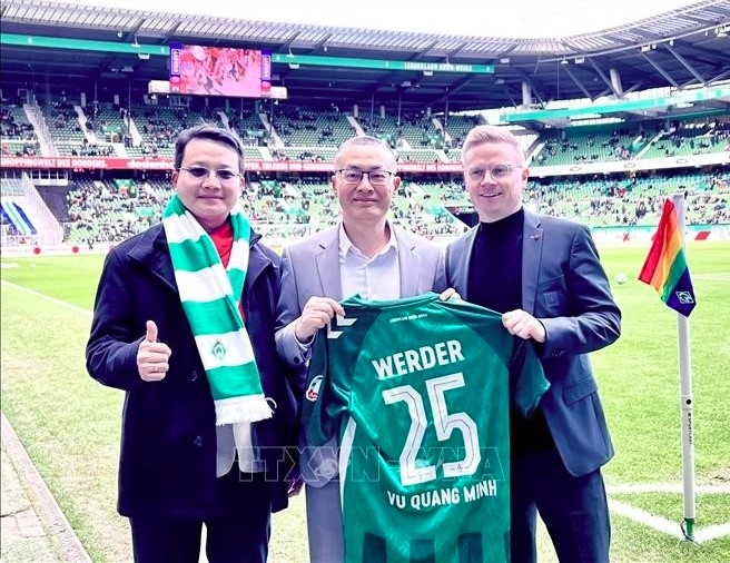 Vietnamese Ambassador to Germany Vu Quang Minh (C) presented with a jersey from Werder Bremen club