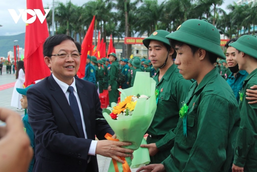 Ho Quoc Dung, secretary of Binh Dinh province's Party Committee, hands flowers to young people who have enlisted to serve in the military.
