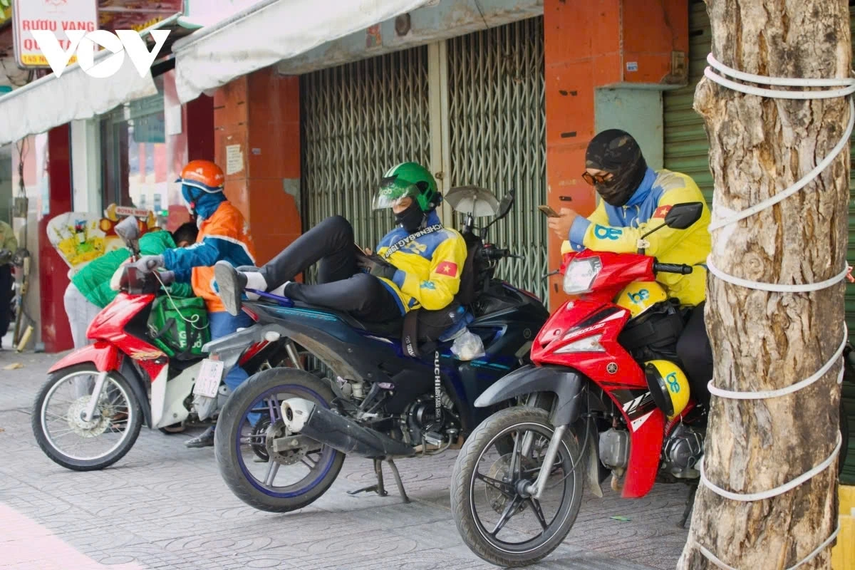 Shippers and ride-hailing drivers seek shade under trees to rest, but they remain fully covered like “ninjas”. Constantly moving under the sun, they face dehydration, exhaustion, and even heatstroke.