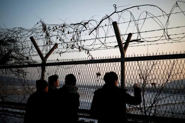 Du khách nhìn sang phía Triều Tiên qua hàng rào dây thép gai phân chia hai miền. Ảnh AFP.