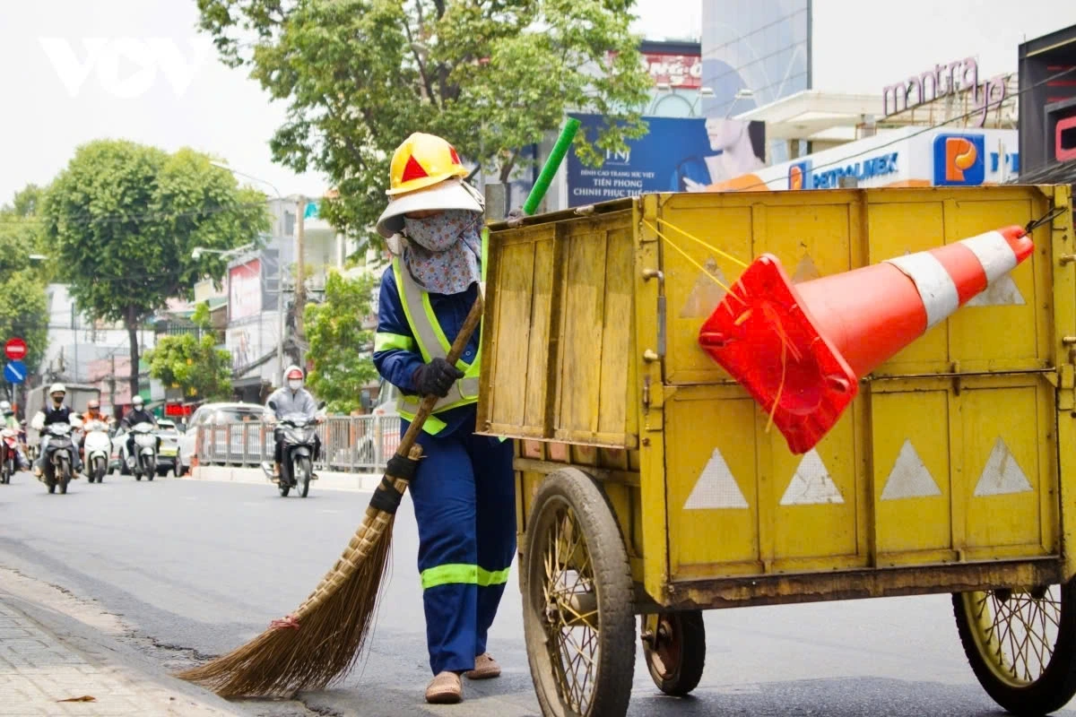 Sanitation workers continue sweeping the streets even as sweat drenches their clothes.