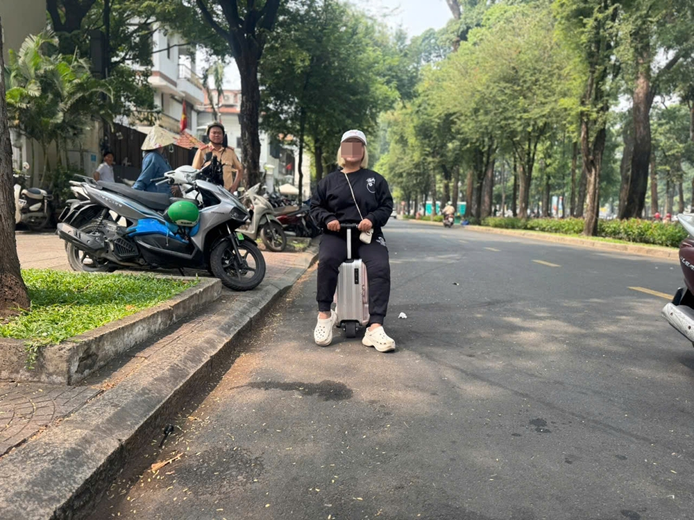 Bà T.T.N.T. "cưỡi" vali di chuyển ở đường Lê Duẩn, quận 1. Ảnh: Phòng CSGT