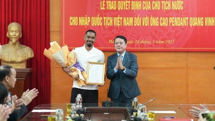 A representative of the Hanoi Department of Justice hands over the decision to footballer Cao Pendant Quang Vinh (left). (Photo: nhandan.vn)