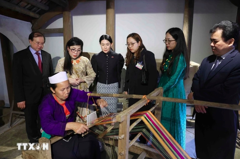 Bà Lê Thị Bích Trân, Phu nhân Thủ tướng Phạm Minh Chính và bà Loo Tze Lui, Phu nhân Thủ tướng Cộng hòa Singapore Lawrence Wong nghe Nghệ nhân giới thiệu về kỹ thuật dệt vải thổ cẩm. (Ảnh: Phạm Kiên/TTXVN)