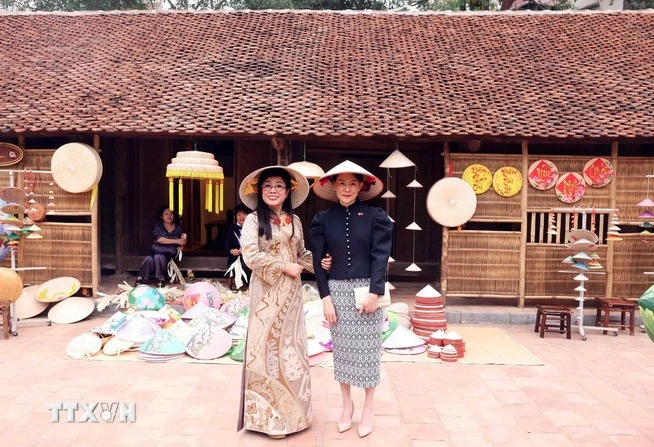 Bà Lê Thị Bích Trân, Phu nhân Thủ tướng Phạm Minh Chính cùng bà Loo Tze Lui, Phu nhân Thủ tướng Cộng hòa Singapore Lawrence Wong đội nón lá chụp ảnh lưu niệm tại Bảo tàng Dân tộc học Việt Nam. (Ảnh: Phạm Kiên/TTXVN)
