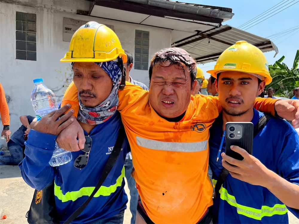 Các công nhân hỗ trợ người bị thương rời khỏi tòa nhà