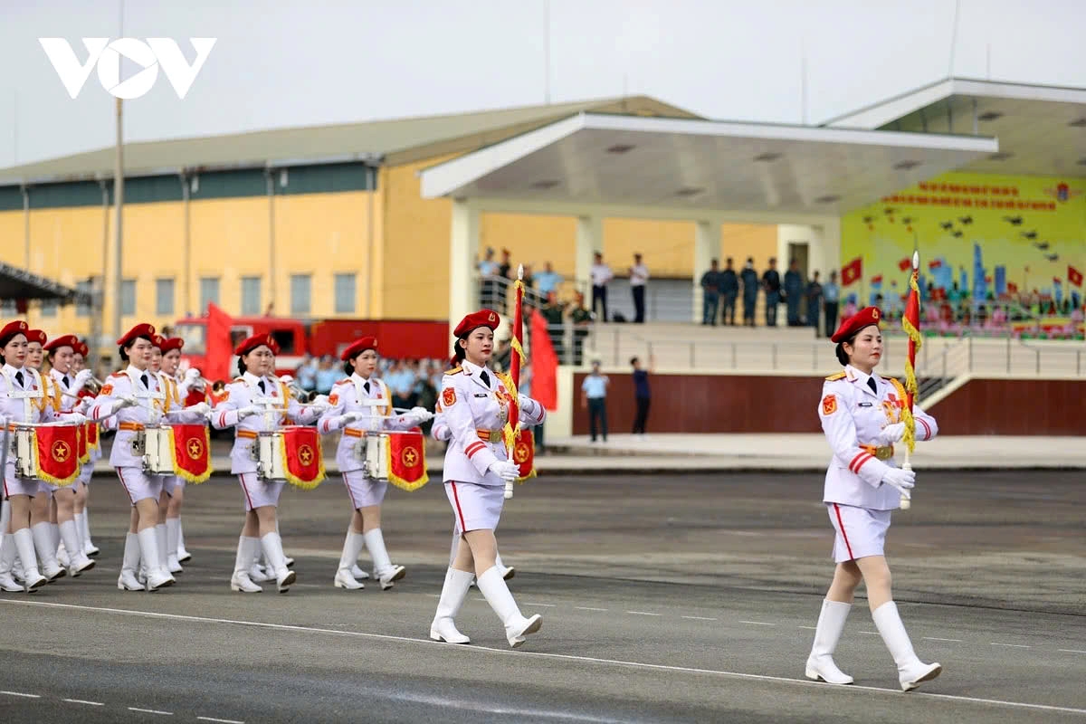 Behind them, the female military band formation marches past the grandstand with resounding music.