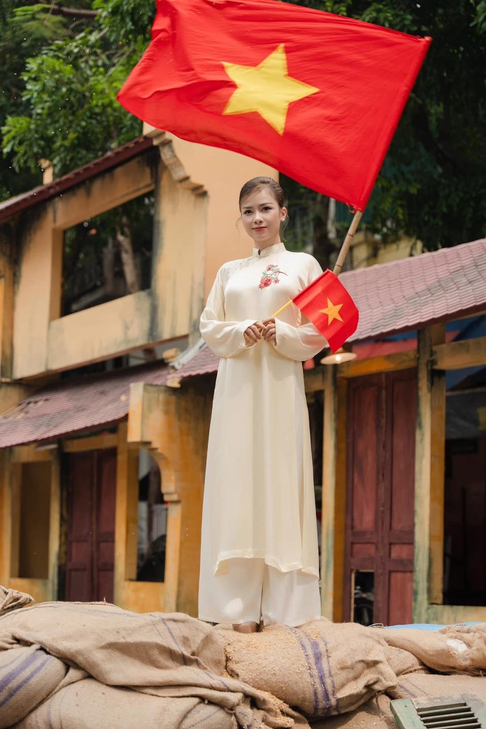 Dương Hoàng Yến mặc áo dài, cầm cờ đỏ sao vàng nhân dịp kỷ niệm 50 năm Ngày Giải phóng miền Nam. (Nguồn: FBNV)