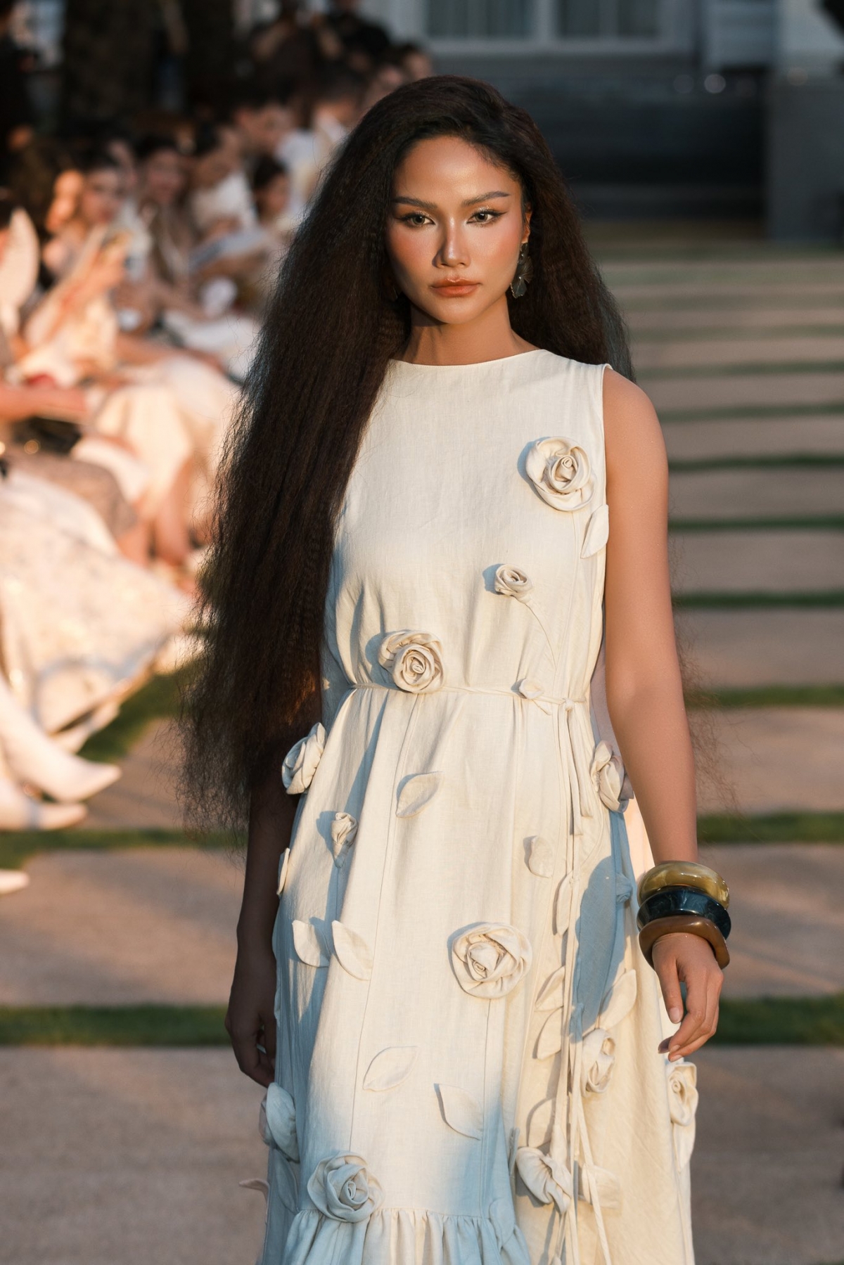 Hoa hậu H'Hen Niê lộ bụng lùm lùm khi catwalk tại một sự kiện thời trang. Người đẹp diện mẫu đầm maxi đính hoa bay bổng, phom suông rộng giấu đường cong nhưng vẫn lộ vòng hai nhô cao giữa tin đồn mang bầu. Giữa đồn đoán từ cư dân mạng, cả H'Hen Niê và chồng đều không lên tiếng.