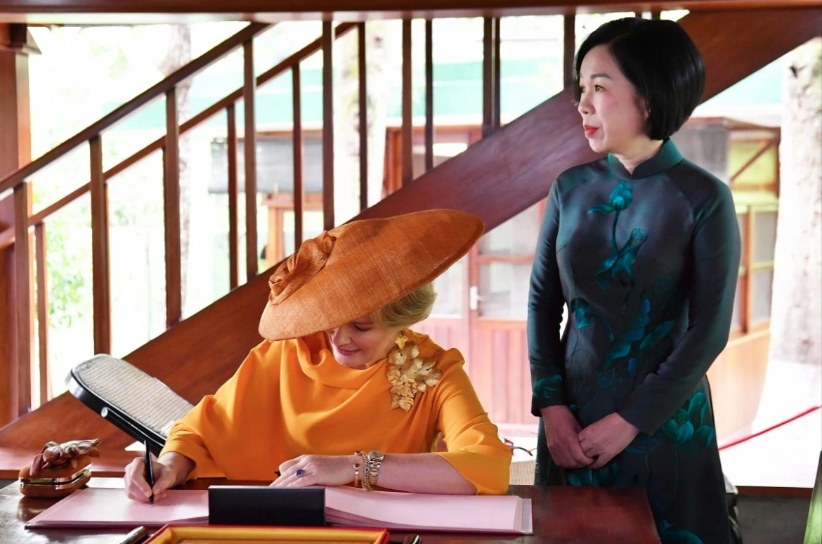 Queen Mathilde writes in the guestbook, expressing her impressions of the visit to the Ho Chi Minh Relic Site.
