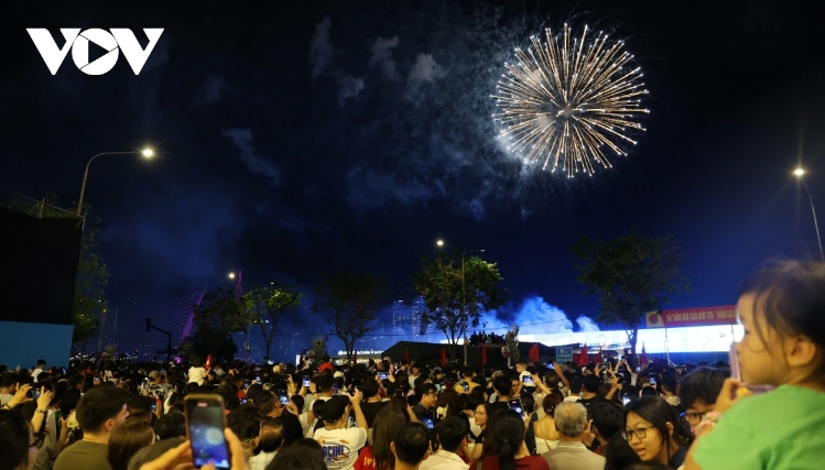 Crowds of people gather in the riverside park area