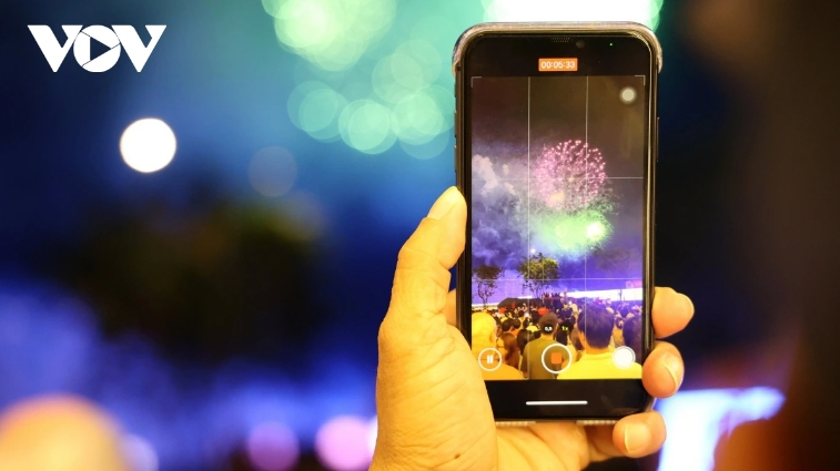Local residents use their phones to record the fireworks spectacle