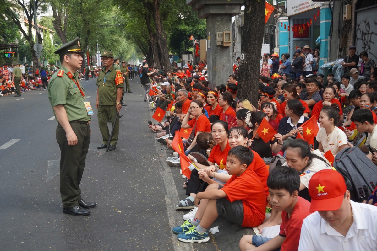 Mọi người ngồi trật tự 2 bên vỉa hè để chờ đợi các khối diễu binh, diễu hành. 