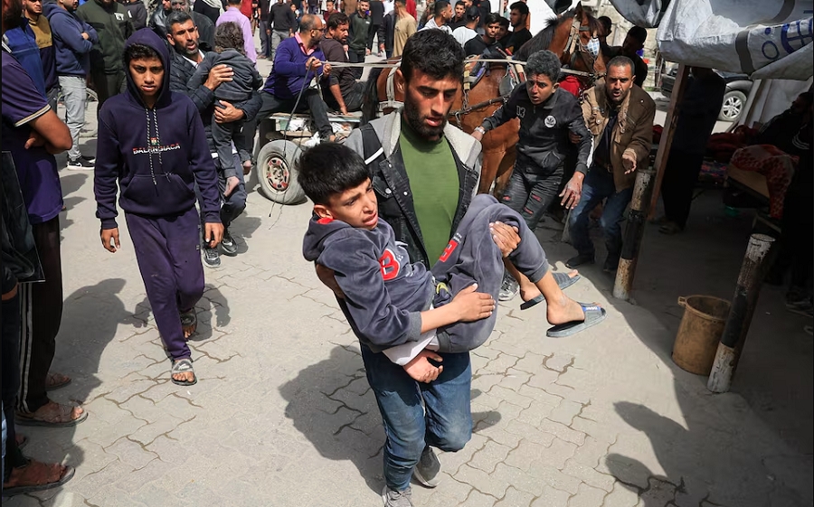 Người đàn ông đưa đứa trẻ đến bệnh viện sau cuộc không kích tại thành phố Gaza. Ảnh: Reuters