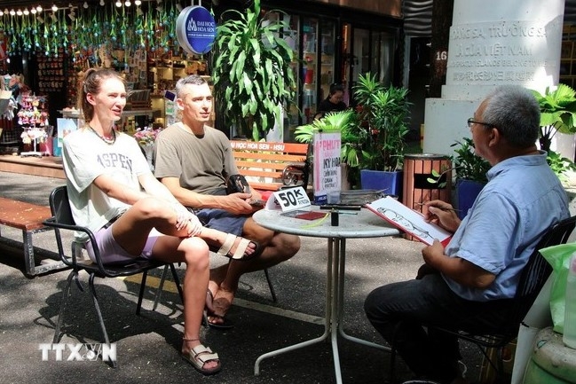 Foreign tourists enjoy a painting service in Nguyen Van Binh book street in Ho Chi Minh City.