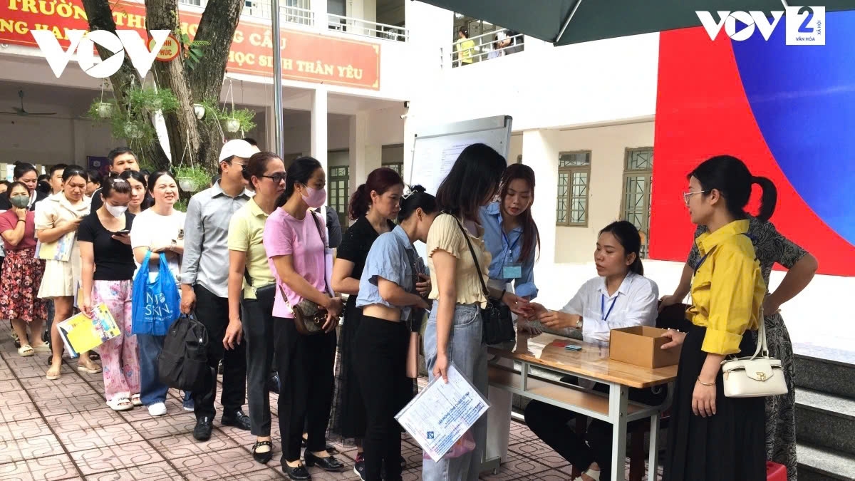 Nhiều phụ huynh mang theo hồ sơ đến cổng trường đễ xếp hàng xin học cho con.