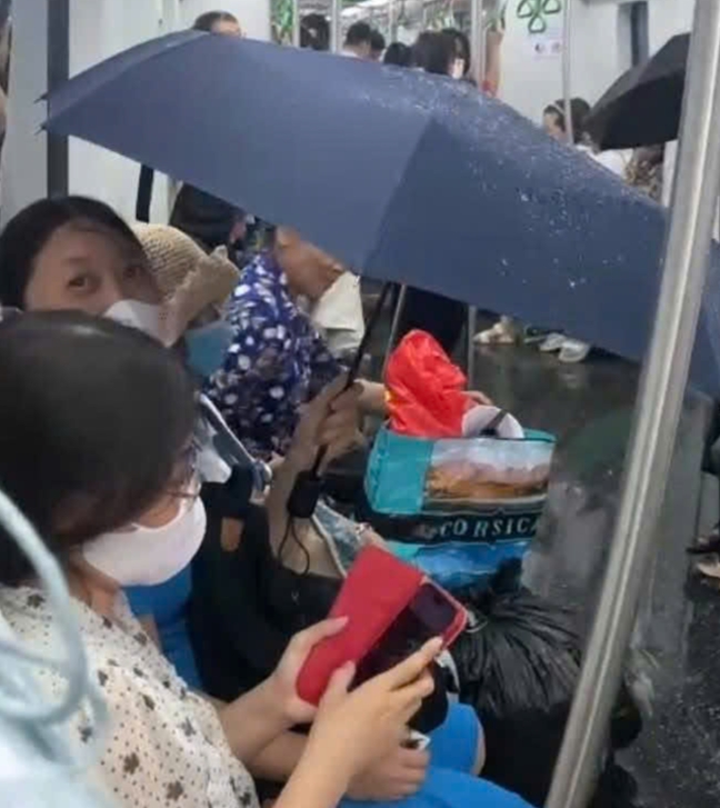 Hành khách phải che ô trên chuyến tàu điện Cát Linh - Hà Đông vào chiều tối 19/5. Ảnh: H.Q.