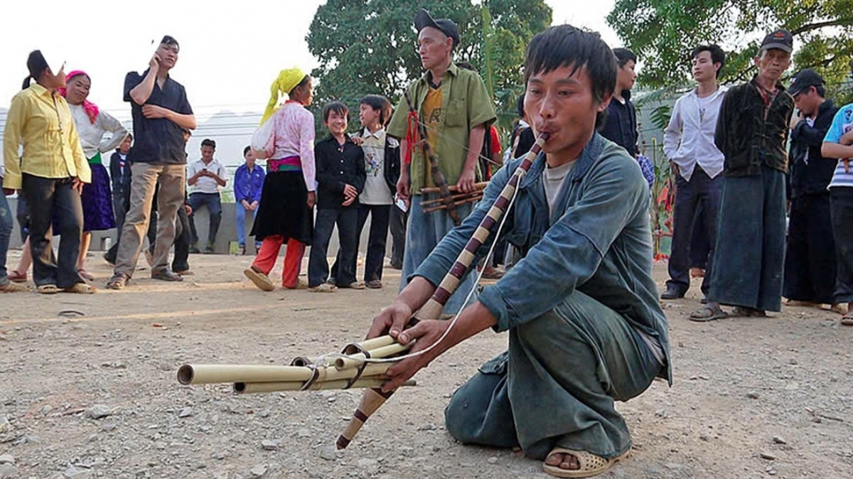 A young H’Mong man plays the khèn (bamboo flute) at Pho Cao market.