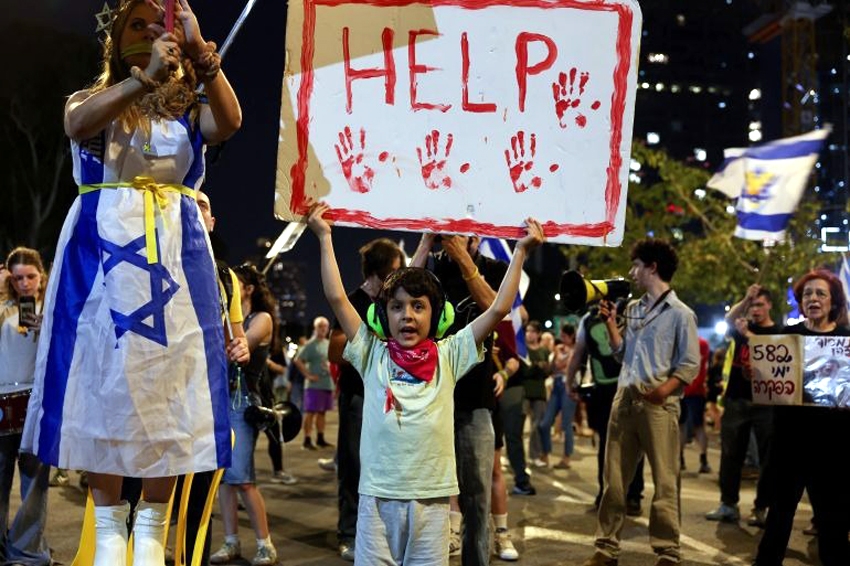 Một đứa trẻ cầm tấm biển trong cuộc biểu tình ở Tel Aviv, Israel - Ảnh: Reuters