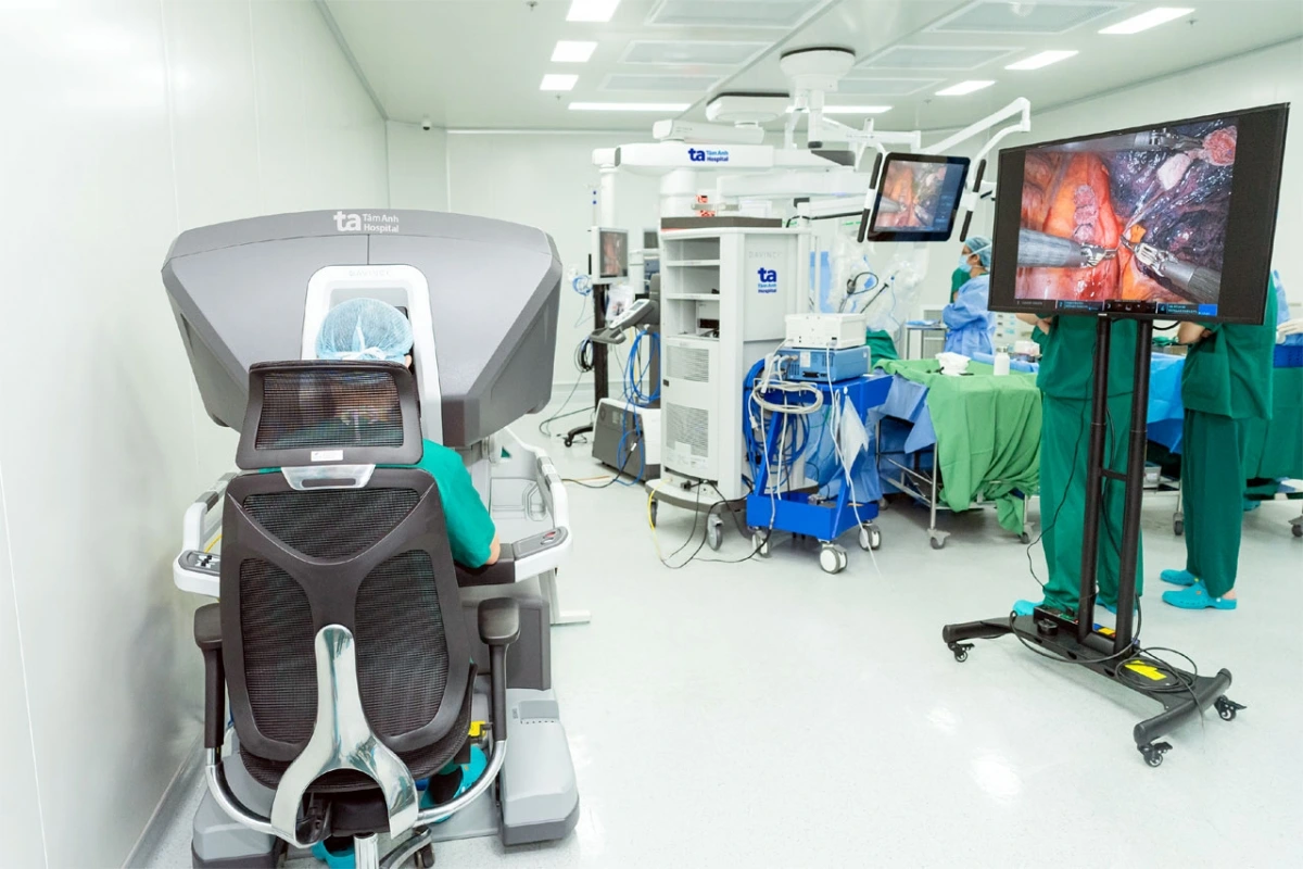 BS.CKII Trần Công Quyền ngồi ở buồng điều khiển chính, điều khiển bốn cánh tay robot thao tác cắt khối u, phối hợp nhịp nhàng cùng bác sĩ phụ mổ - Ảnh: BVĐK khoa Tâm Anh