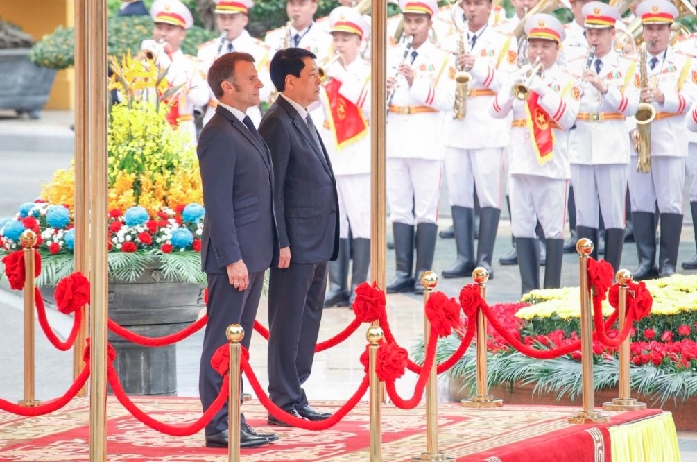 The two leaders stand on the podium while military bands play the national anthems of both nations.