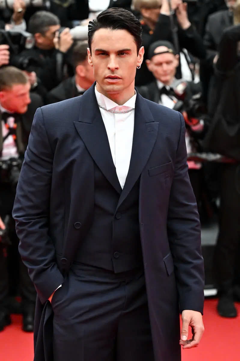 Baptiste Giabiconi diện bộ suit màu xanh navy gồm áo khoác dài, áo vest và quần tây cùng màu.