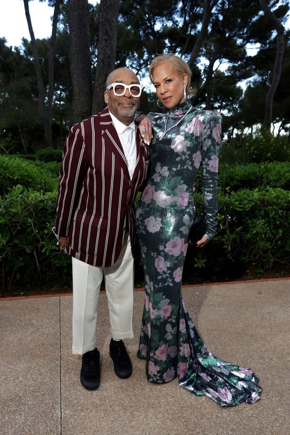 Tại liên hoan phim Cannes 2025, Spike Lee mặc áo vest kẻ sọc của thương hiệu Ralph Lauren x Morehouse với quần trắng. Tonya Lewis Lee chọn váy dài bó sát với họa tiết hoa.