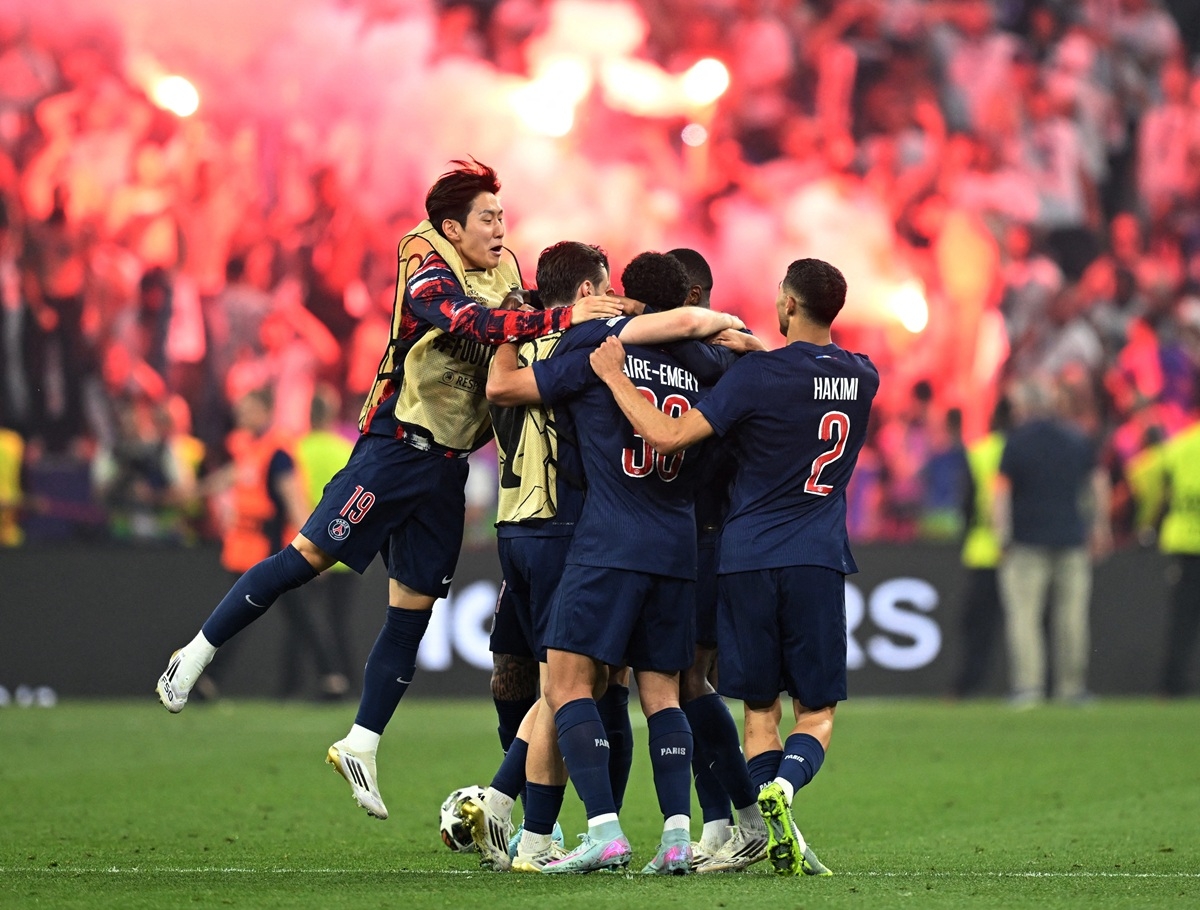 Các cầu thủ PSG lao vào sân ăn mừng khi các CĐV đốt pháo sáng trên khán đài. 