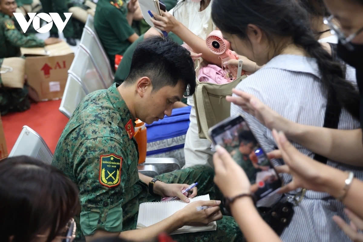 Captain Le Hoang Hiep from Division 9, Corps 34, who becomes famous after the clip of him stepping down from the vehicle during the rehearsal parade for the 50th anniversary of the liberation of the South and national reunification in late April, is surrounded by people at the station.