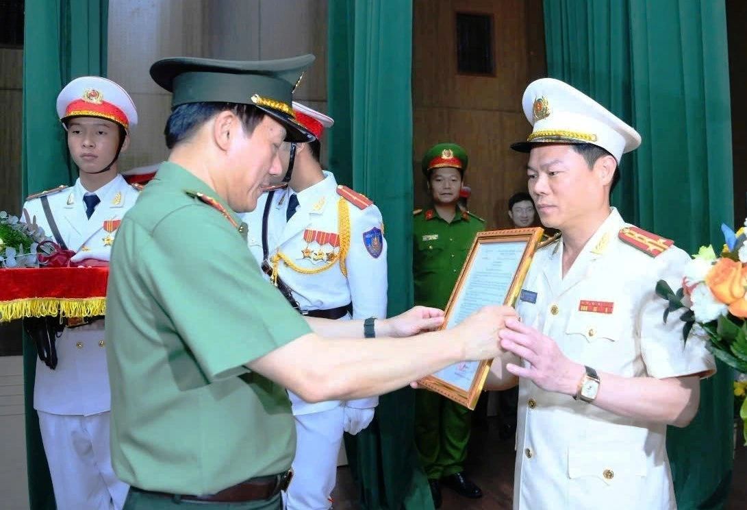 Đại tá Nguyễn Hữu Mạnh nhận quyết định từ Bộ trưởng Bộ Công an - Đại tướng Lương Tam Quang.
(Ảnh: Bộ Công an)