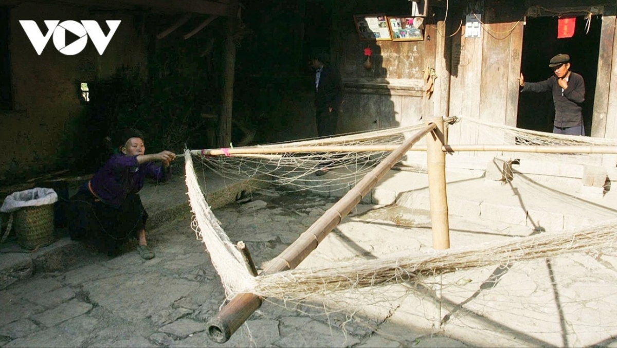 A Mong ethnic woman makes linen in the yard of a hundred-year-old house.