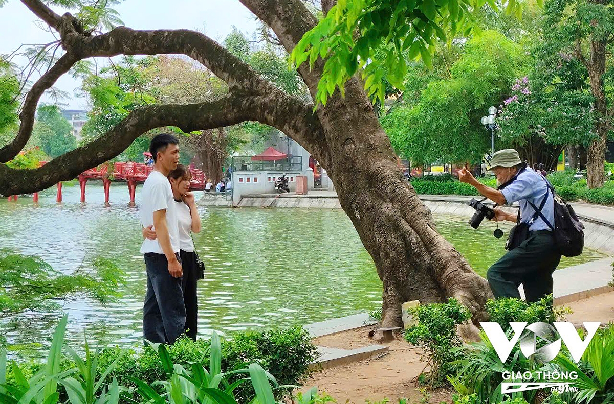 Người thợ ảnh già nhẹ nhàng hướng dẫn khách tạo dáng bên hồ.
