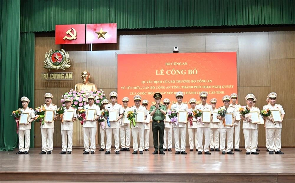 Bộ trưởng Lương Tam Quang trao Quyết định và tặng hoa chúc mừng các giám đốc công an địa phương sau sáp nhập. (Ảnh: Bộ Công an)