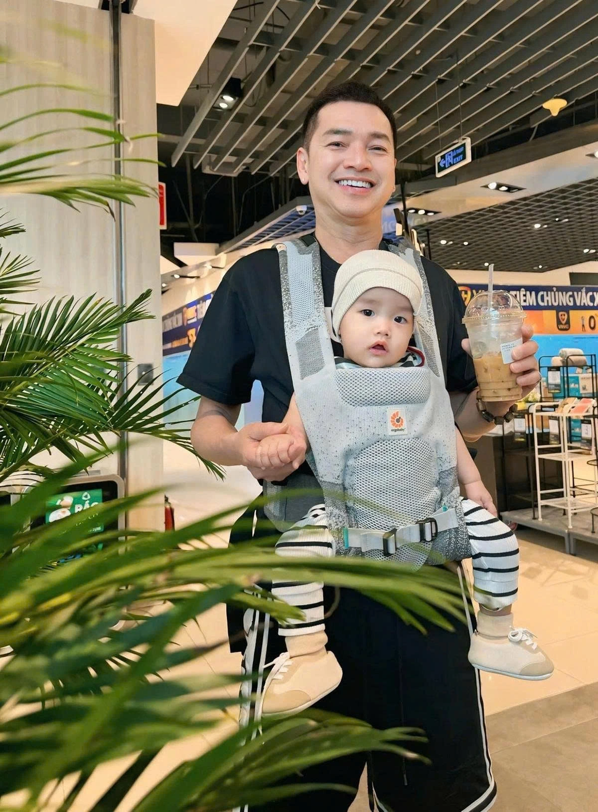 Quang Minh địu con trai đi dạo. Em bé được nhận xét càng lớn càng giống bố.