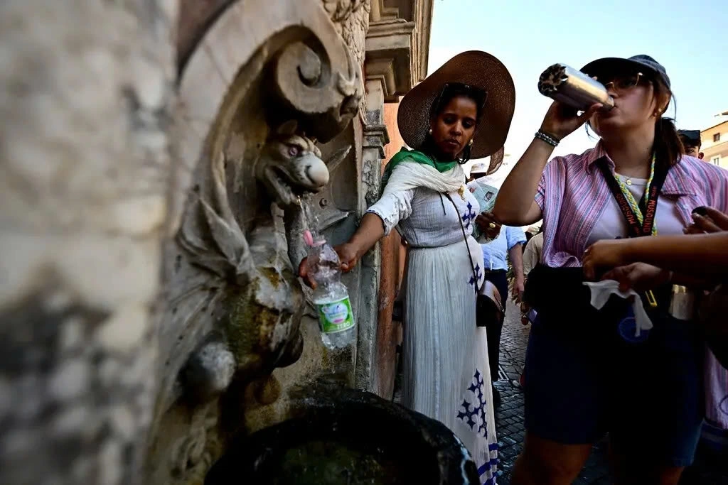 Người dân uống nước giải nhiệt từ các vòi công cộng ở Vatican. (Ảnh: Reuters)