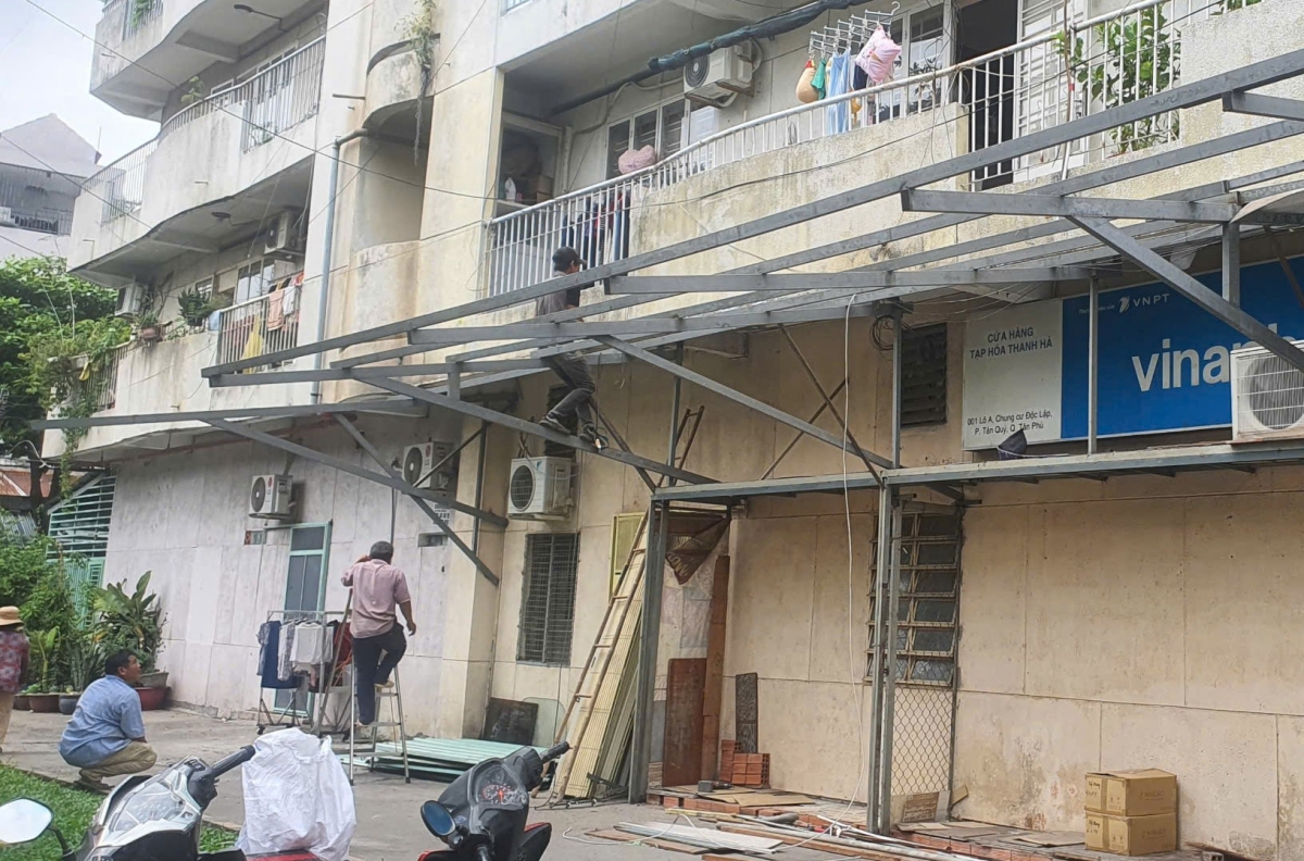Người dân thuê thợ tháo dỡ phần khung sắt, mái tôn, cửa sắt, cửa cuốn xây lấn chiếm hành lang chung cư Độc Lập. Ảnh: AH